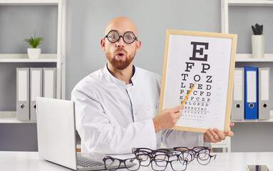 Funny optician male doctor checking a patient's vision sitting at desk on workplace in...