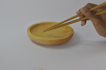 close up of wooden plate with chopsticks held by adult hand, isolated on white background