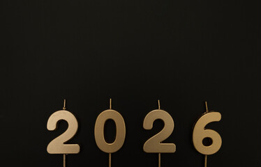 2026 Happy New Year. Top view of gold numbers on black background. Copy space, flat lay.