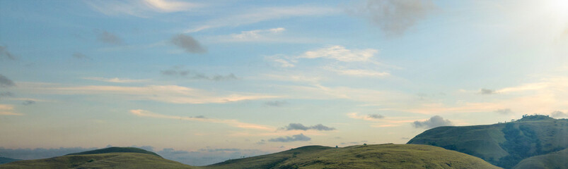 Mountain range with blue sky and clouds in the background. The sky is clear and the clouds are fluffy