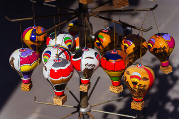 A vibrant collection of colorful hot air balloons suspended from a pole in souvenir shop