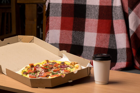 Delicious pizza in a box with melted cheese, tomatoes, and ham on a wooden table. Perfect for take-out or delivery meal options. 