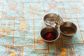 Oriental three distinct metal bowls filled with various spices placed on a table