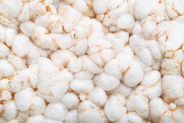 Close-up view of a cluster of white rice cakes or rice crispbreads. The unique texture of the puffed rice grains, with each grain appearing soft, airy, and lightly browned in some areas.