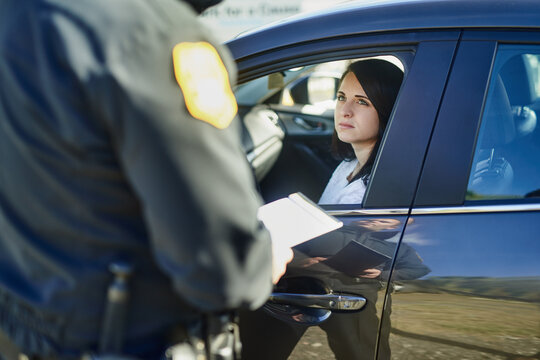 Writing, woman and traffic officer with ticket for checkpoint, security and crime investigation on highway. Policeman, law and driver registration for car accident, dui or road safety with suspect