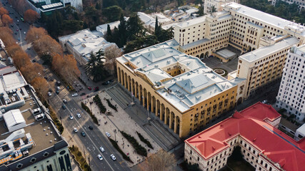 Bustling aerial view of tbilisi's rustaveli avenue with cars driving past the imposing parliament building, showcasing the city's architectural landscape