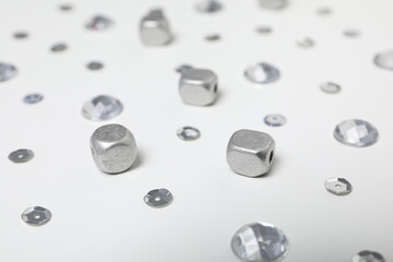 Sequins and beads of silver color on white background, close up