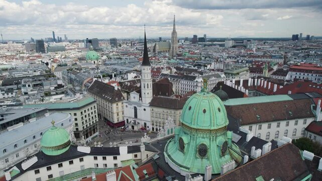 Aerial orbiting shot over iconic Michaelerplatz Square with Hofburg Palace and St. Michael Church, Vienna