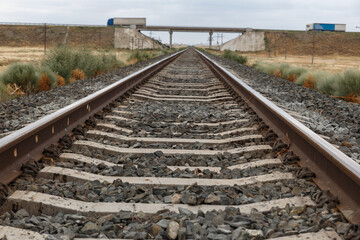Railway tracks in rural areas in Kazakhstan. A road bridge is in the background.