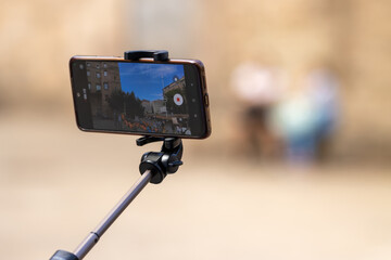 Smartphone on selfie stick recording outdoor scene in urban setting
