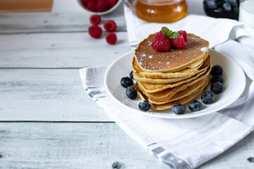 Pancakes with fresh berries and honey. on a wooden background. breakfast