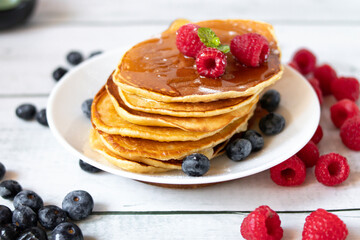 Pancakes with fresh berries and honey. on a wooden background. breakfast