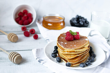 Pancakes with fresh berries and honey. on a wooden background. breakfast