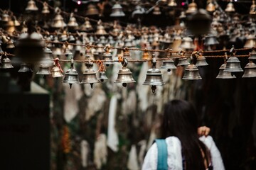 Woman amidst hanging bells in a spiritual setting.
