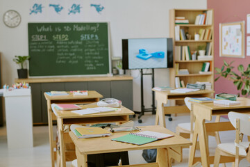 Well-organized classroom setup with study materials neatly arranged on tables and a chalkboard in...