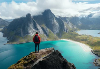 A man stands on a mountain top overlooking a beautiful lake