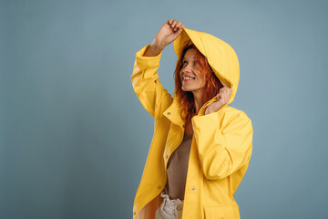 Ready for the rain, in yellow coat. Woman is in the studio against background