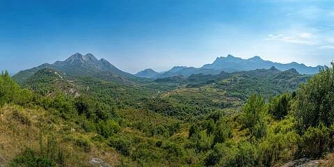 A panoramic view of mountains and lush greenery under a clear blue sky.