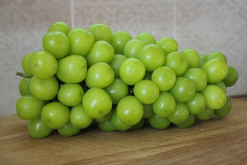 Shine Muscat grapes. Close-up of a bunch of green grapes. Fruit on a wooden board.