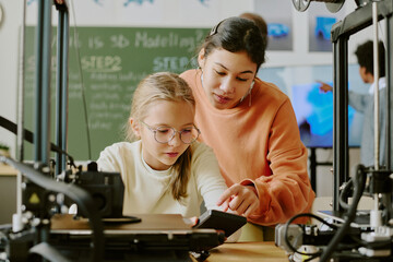Young students collaborating on a 3D printing project in a technology class setting, focusing on...