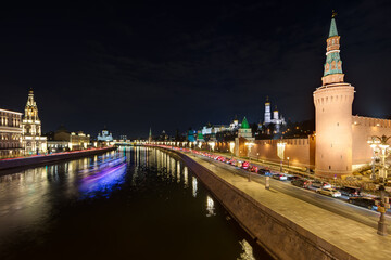 Fototapeta premium Moscow, Russia. Evening view of the Moscow River, the Kremlin embankment and the towers of the Moscow Kremlin. Historical center of Moscow. Blurred light from a sailing ship at a long exposure.
