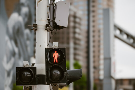 Close-up shot of a red pedestrian crossing signal against a backdrop of tall buildings, representing urban safety and the flow of modern city life.