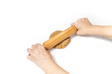 hands kneading homemade oatmeal cookie dough with a rolling pin