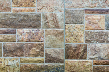 Close-up of masonry made of porcelain stoneware tiles of various sizes and shapes, stylized as antique