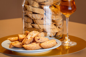Almond cantucci biscuits in focus with Vin Santo and jar blurred in background creating a stylish...