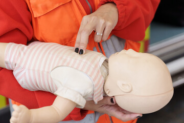 Close-up of paramedic practicing infant CPR on a training mannequin