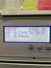 Digital water tester provides accurate readings of crystal clear water with beige tiled floor,...