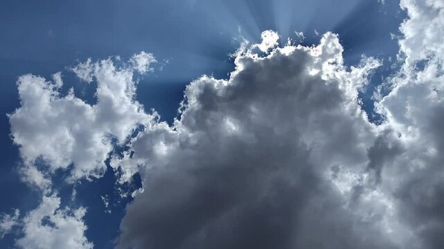The big dark cloud blocks the sun but it can't stop the sun's rays from coming out everywhere