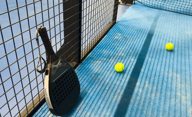 Paddle racket with a ball. Padel court in summer.