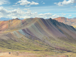 Fototapeta premium Breathtaking panoramic view of Palccoyo Rainbow Mountain in Peru, less touristy than Vinicunca, but more accessible from Cusco for travellers and tourists. Bright sunny day, tiny people in landscape.