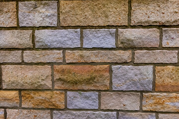 A close-up of a rough, textured stone wall with a variety of colors and sizes