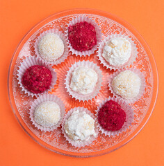 Various colored truffles on a orange background and transparent plate. Copy space.