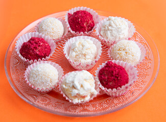 Various colored truffles on a orange background and transparent plate. Copy space.