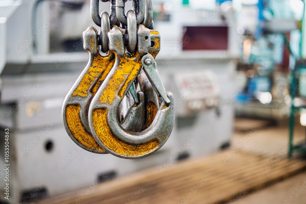 Poster heavy-duty lifting device with hooks in an industrial workshop, used for moving substantial loads in