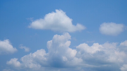 Obraz premium The shapes, patterns and textures of white clouds clump together in the blue sky. The daytime sky looks cloudy. Unique and abstract shape of white clouds for graphic design or banner background