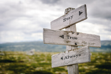 stay true always text quote written on wooden signpost at the crossroads outdoors in nature.