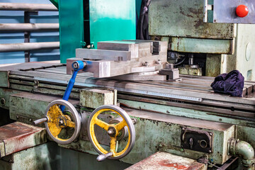 A close-up view of an industrial milling machine in an active workshop showing precision machining processes in action, with tools and equipment in sight
