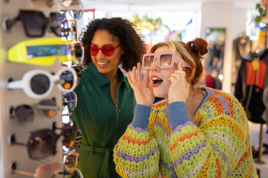 Female friends trying on sunglasses in a store on vacation