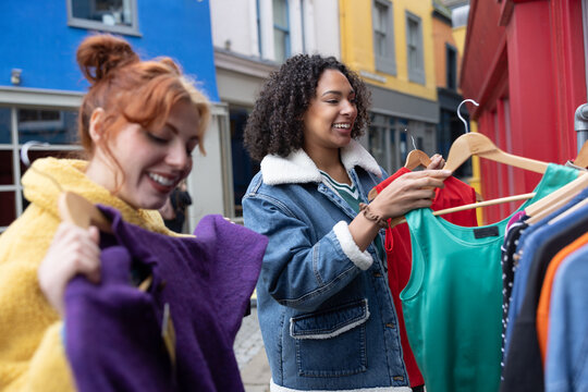 Friends looking through a vintage clothes sale rail at a street market