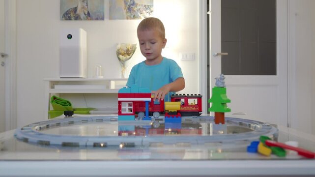 Happy child little boy having fun playing steam train set with sound, light, and action bricks.