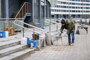 Fototapeta premium A man is diligently working on the sidewalk in front of a building