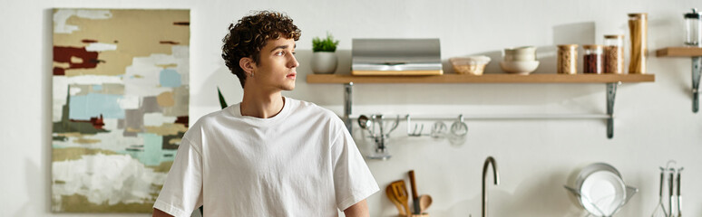 A handsome young man standing in a stylish kitchen.