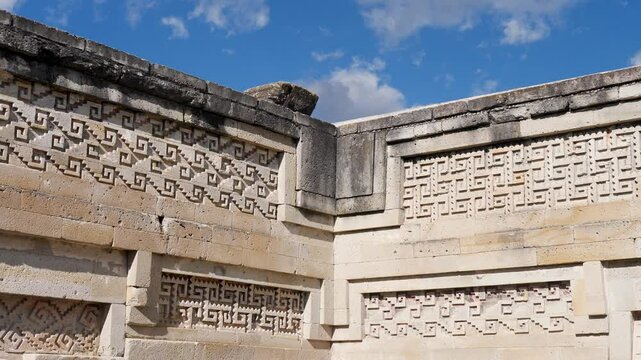 Slow motion landscape of Zapotec culture ancient patterns and historic shape carvings on stone rock wall Mitla archaeology ruins site Oaxaca Mexico landmark hieroglyphs sacred