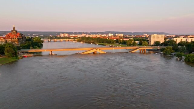 Drone video of Dresden during a flood with warm light highlighting the damaged Carola Bridge as the main focus. Drone move right