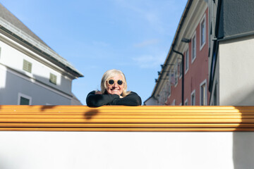 Cheerful woman with sunglasses enjoys sunny urban day in european city