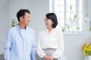 家のリビングで過ごす笑顔のミドル夫婦
